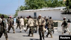 FILE - Somali soldiers patrol at the front gate of the presidential palace following a suicide bomb attack in Mogadishu, Jan. 29, 2013. 