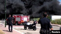 Israeli policemen stand next to smoke from a fire following incoming rockets from Lebanon to Israel in Bezet, northern Israel, April 6, 2023.