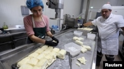 Pantelis Panteli (R) and a worker prepare halloumi on his farm in Kokkinotrimithia, Cyprus February 10, 2024. (REUTERS/Yiannis Kourtoglou)