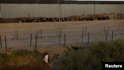 Un migrante que busca asilo en los Estados Unidos pasa por una valla de alambre de púas desplegada para inhibir el cruce de migrantes a los Estados Unidos, vista desde Ciudad Juárez, México, el 28 de noviembre de 2023.