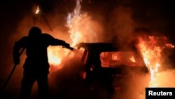 A French firefighter works to extinguish a burning car during the fifth day of protests following the death of Nahel, a 17-year-old teenager killed by a French police officer in Nanterre during a traffic stop, in Tourcoing, France, July 2, 2023.