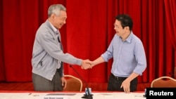 Perdana Menteri Singapura Lee Hsien Loong berjabat tangan dengan Menteri Keuangan Lawrence Wong di Singapura, 16 April 2022. (Foto: SPH Media/The Straits Times/Lim Yaohui via REUTERS) 