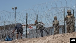 Sejumlah migran tampak berusaha melewati kawat berduri yang dipasang di area perbatasan AS-Meksiko. Mereka berusaha masuk ke wilayah El Paso, Texas, dari Ciudad Juarez, Meksiko, pada 11 Mei 2023. (Foto: AP/Christian Chavez)