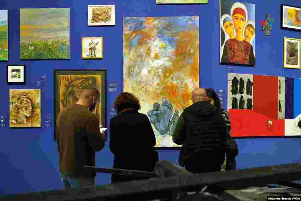 Varias personas conversan junto a la obra “Bloqueo" del artista gazatí Hani Zurob, que busca golpear al visitante con sus pies.