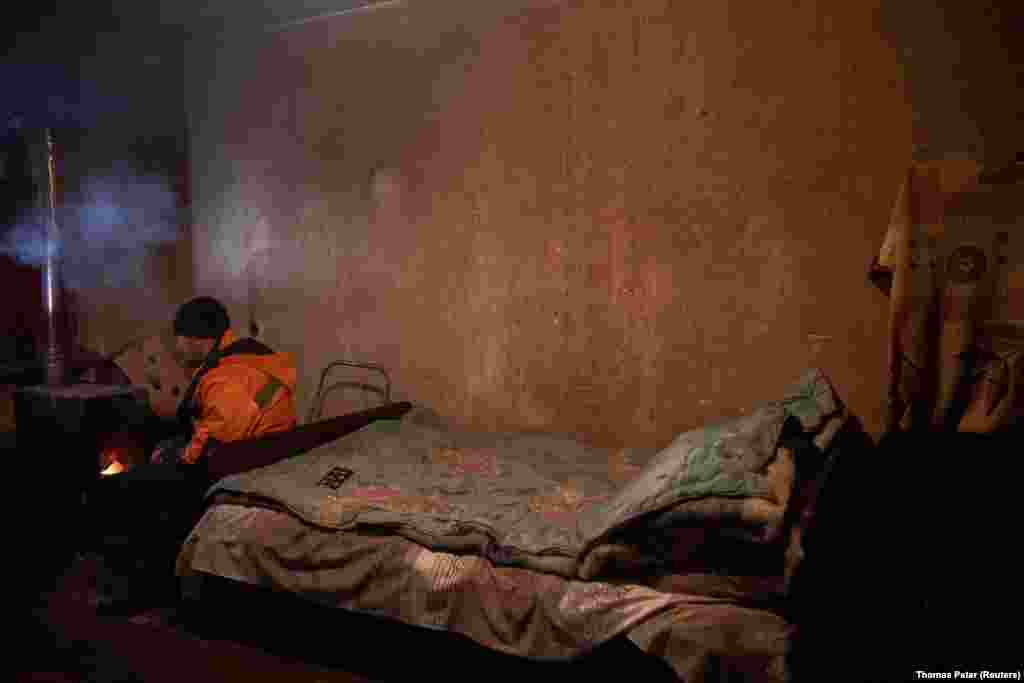 Viktor Ivanovich, de 35 años, intenta calentarse en su apartamento dañado, al que le volaron las ventanas durante los combates en el invierno anterior.