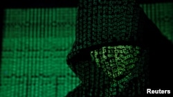 FILE - Binary code is projected onto a hooded person in this illustration photo taken on May 13, 2017. (TPX Images via Reuters)