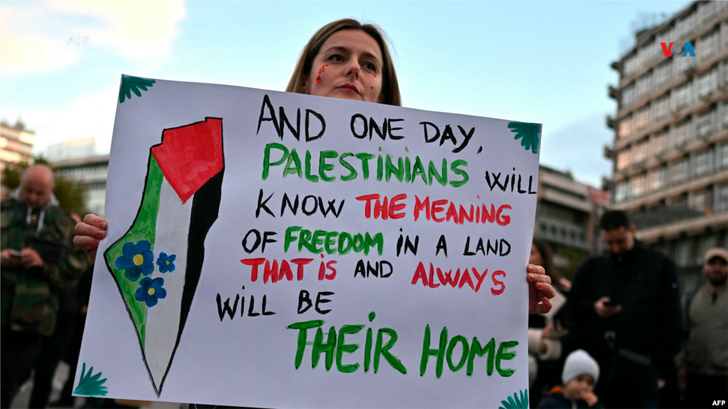 Mujer manifestante apoya al pueblo palestino en Belgrado, capital de Serbia. El cartel que sostiene dice: "Y un día, los palestinos sabrán el significado de la libertad y de la tierra que es y será siempre su hogar".