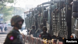 FILE - Tentara berdiri di samping kendaraan militer ketika orang-orang berkumpul untuk memprotes kudeta militer, di Yangon, Myanmar, 15 Februari 2021. (REUTERS/Stringer)
