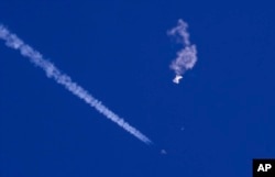 Sebuah pesawat jet tempur AS terbang di dekat sisa balon besar yang ditembak rudal di atas Samudera Atlantik, di lepas pantai South Carolina, AS, 4 Februari 2022. (Foto: Chad Fish via AP)