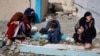 People rest next to damaged buildings as Palestinian arrive in Rafah after being evacuated from Nasser Hospital in Khan Younis due to the Israeli ground offensive against Hamas, in the southern Gaza Strip, Feb. 15, 2024.