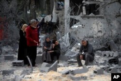 Palestinians sit on the rubble of a destroyed house following Israeli airstrikes on the town of Khan Younis, southern Gaza Strip, Nov. 22, 2023.