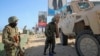FILE - Ugandan peacekeepers with the African Union Transition Mission in Somalia (ATMIS) stand next to their armored vehicle on a street in Mogadishu, Somalia, May 10, 2022.