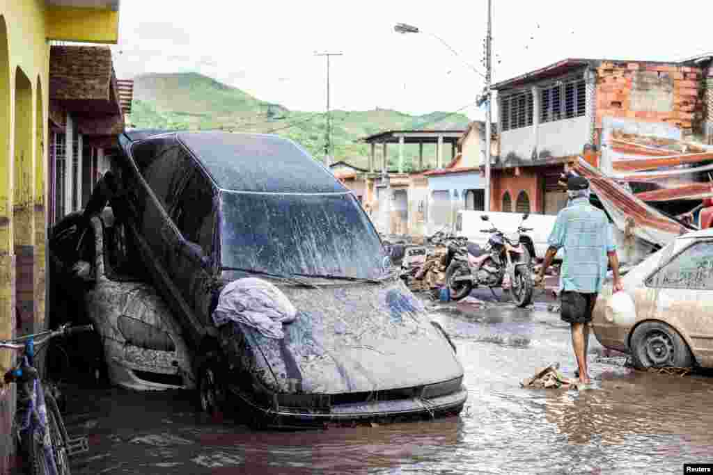 A man walks near damaged vehicles after devastating floods swept through the town after Hurricane Beryl passed off the Venezuelan coast, in Cumanacoa, Venezuela, July 2, 2024.