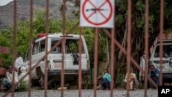 FILE - An ambulance said by residents to have been damaged and stripped for parts by Eritrean soldiers sits next to people as they wait to be seen at a medical clinic in Abi Adi, in the Tigray region of northern Ethiopia, May 11, 2021.