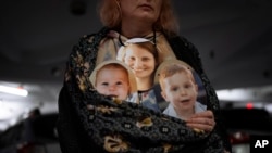 Des photos de Shiri Bibas et ses fils Kfir, 9 mois, et Ariel, 4 ans, lors d'une manifestation pour leur libération, à Tel Aviv, le 21 février 2024. Le Hamas a dit qu'il remettrait leurs corps à Israël dans le cadre de la 1e phase de la trêve s'achevant le 1er mars. (Photo AP)