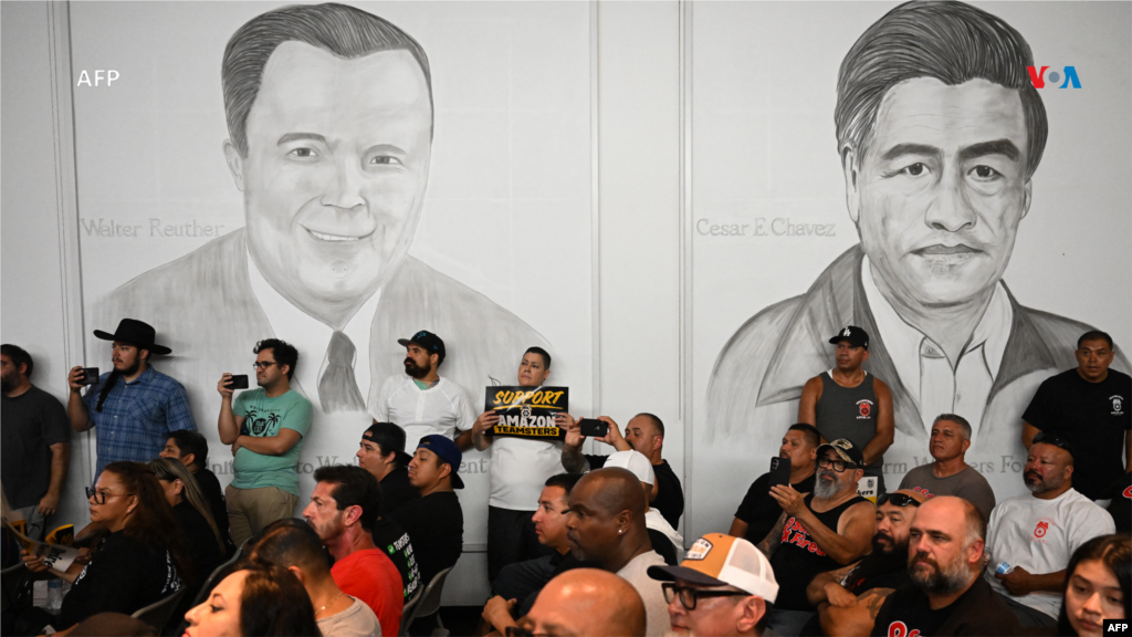 Una persona sostiene un cartel en apoyo de los trabajadores de Amazon debajo de los murales del líder de la UAW, Walter Reuther, y del líder sindical de la UFW, César Chávez, durante una manifestación con trabajadores y miembros del sindicato como parte del “Día de Solidaridad de los Teamsters de Amazon” en apoyo de la sindicalización y la negociación colectiva. 