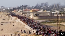 Palestinos esperan a que los camiones de ayuda crucen en el centro de la Franja de Gaza el 19 de mayo de 2024.