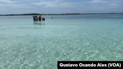 Un vendedor de comida camina en el mar en busca de clientes que pasan tiempo en el cayo conocido como Bajo 360 en el estado Falcón, en el occidente de Venezuela, el viernes 25 de agosto de 2023.
