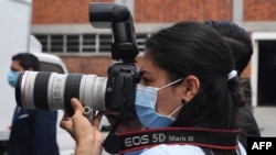 Una fotorreportera usa una máscara quirúrgica durante una conferencia de prensa en San Salvador el 21 de abril de 2020.