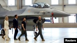 Ukrainian President Volodymyr Zelenskiy and Dutch Prime Minister Mark Rutte walk near an F-16, in Eindhoven, Netherlands, Aug. 20, 2023. 