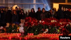 Orang-orang berdiri di depan lilin yang menyala di luar tempat konser Balai Kota Crocus pada hari berkabung yang diumumkan setelah insiden penembakan maut di pinggiran Moskow, Rusia, 24 Maret 2024.