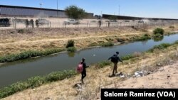 En Ciudad Juárez, México, una mujer camina con su hijo por el borde del Río Bravo buscando entregarse a las autoridades el 11 de mayo de 2023.