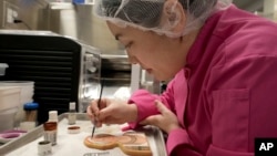 Jasmine Cho works on a cookie portrait of Filipina mambabatok tattoo artist Apo Whang-Od in Pittsburgh, Pa., May 3, 2023. (AP Photo/Matt Freed)