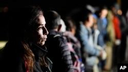 ARCHIVO - Una mujer de Cuba espera con otros migrantes para ser procesados para buscar asilo después de cruzar la frontera hacia Estados Unidos, el viernes 6 de enero de 2023, cerca de Yuma, Arizona.