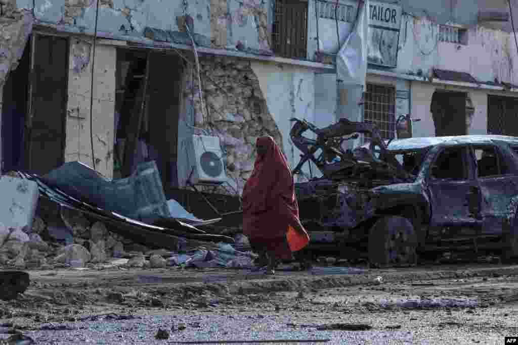 A woman walks past debris and destruction at a cafe where football fans were watching the Euro 2024 final in Mogadishu, Somalia, following a car bomb blast that five people were killed.