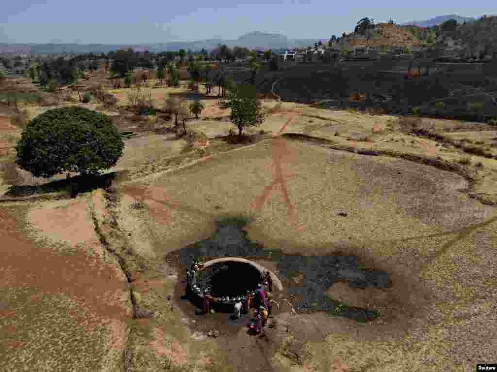 Foto yang diambil dengan menggunakan drone ini memperlihatkan beberapa perempuan tengah mengambil air dari sebuah sumur, di hari yang panas di Kasara, India, 1 Mei 2024.