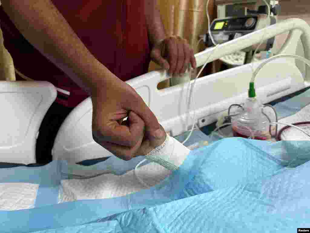 A father holds the hand of his injured child, Tawfik Abu Youssef, in Al-Aqsa Martyrs Hospital, in the aftermath of an Israeli strike, amid the Israel-Hamas conflict, in Deir Al-Balah, in the central Gaza Strip.