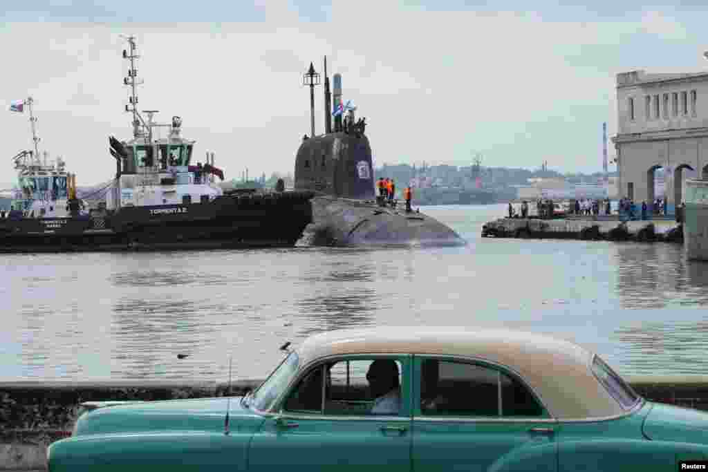 Un coche antiguo pasa mientras el submarino ruso de misiles de crucero de propulsión nuclear Kazán atraca en la bahía de La Habana, Cuba, el 12 de junio de 2024. 