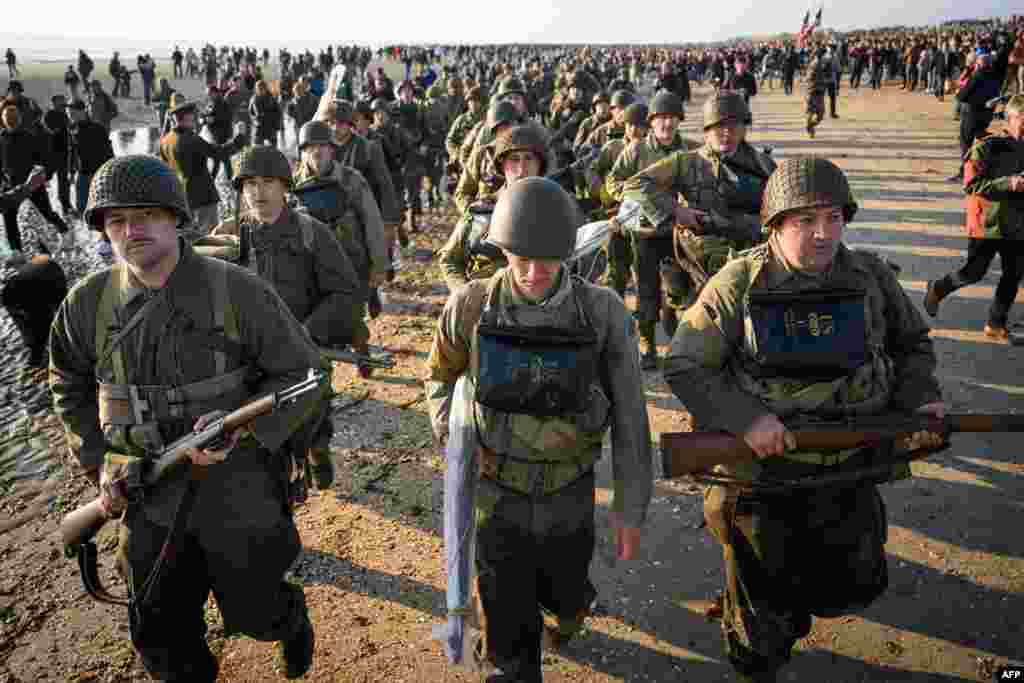 Enthusiasts dressed in replica U.S. Army WWII-era military attire parade along Utah Beach, France, June 6, 2024 during the "D-Day" commemorations marking the 80th anniversary of the World War II Allied landings in Normandy.