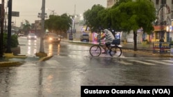 Un hombre pedalea su bicicleta recubierto con una bolsa plástica durante un chubasco en Maracaibo, Zulia, la mañana del 2 de junio de 2023.