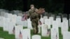 Un soldado del Ejército de EEUU coloca una bandera en una lápida durante el evento anual 'Flags In', antes del Día de los Caídos en el Cementerio Nacional de Arlington en Arlington, Virginia, el 23 de mayo de 2024.