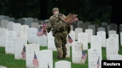 Un soldado de la Vieja Guardia del Ejército de EE. UU. coloca una bandera en una lápida durante el evento anual 'Flags In', antes del Día de los Caídos en el Cementerio Nacional de Arlington en Arlington, Virginia, el 23 de mayo de 2024.