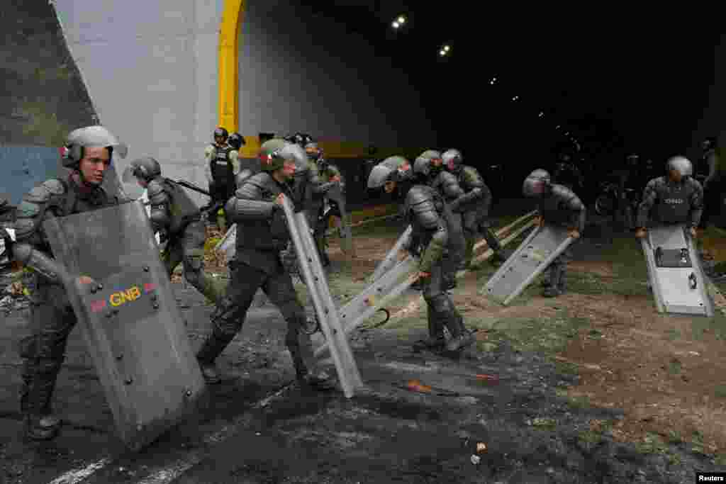 Miembros de la Guardia Nacional Bolivariana de Venezuela usan sus escudos para limpiar una avenida tras protesta en Caracas, el 29 de julio de 2024. 