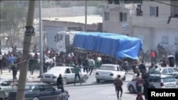 Orang-orang mengejar di belakang konvoi truk bantuan yang melaju ke Gaza dari penyeberangan Rafah, 9 April 2024, dalam tangkapan layar yang diambil dari video. (REUTERS TV/via REUTERS)