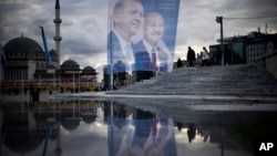 Pedestrians walk past a giant banner of Turkish President and People's Alliance's presidential candidate Recep Tayyip Erdogan, left, at Taksim Square in Istanbul, Turkey, May 10, 2023.