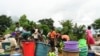 Women and children wash plastic kitchen utensils in a stream in Phalombe, southern Malawi, March 17, 2023.