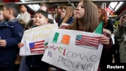 Las familias del personal de la embajada de los Estados Unidos sostienen pancartas cuando el presidente Joe Biden llega al Aeropuerto Internacional de Dublín, en Dublín, Irlanda, el 12 de abril de 2023. REUTERS/Kevin Lamarque