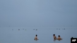FILE - People swim in the ocean off of Crandon Park, July 28, 2023, in Key Biscayne, Fla (AP Photo/Rebecca Blackwell, File)