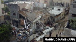 Orang-orang berkumpul di depan bangunan yang terkena serangan udara oleh Israel di Kota Gaza, Sabtu, 13 Mei 2023. Israel dan Gaza saling menembakan artileri berat pada 12 Mei, tetapi Mesir berhasil memediasi untuk menghentikan konflik. (Foto: Mahmud Hams/AFP)