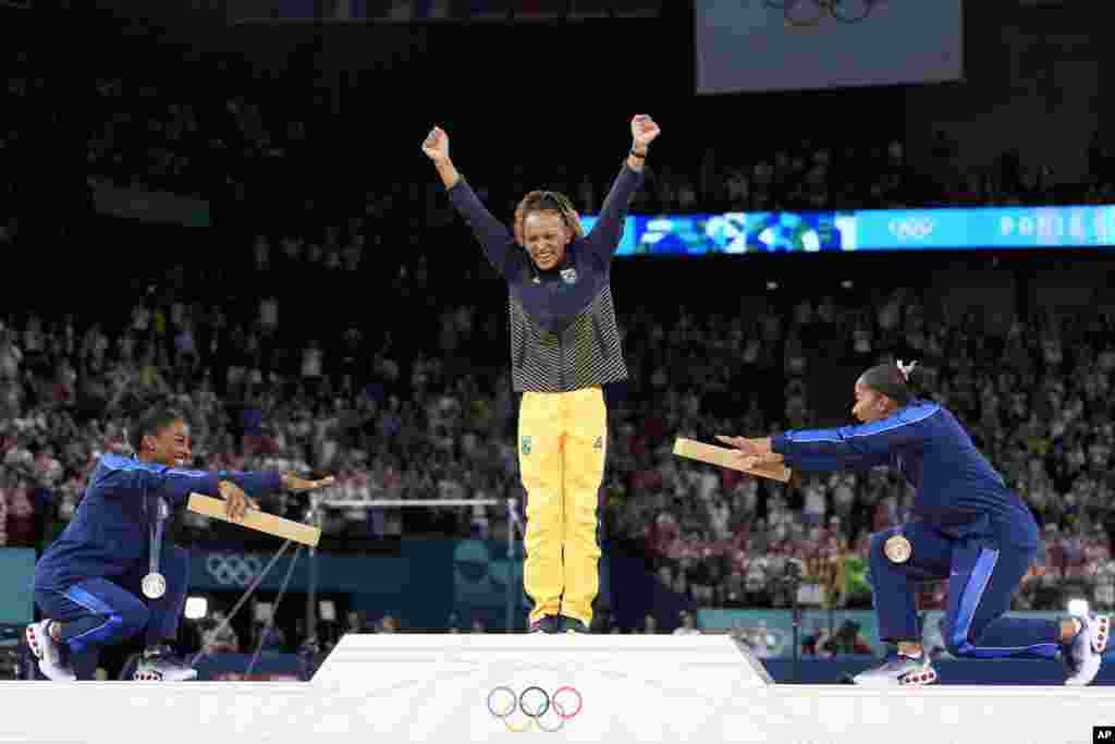 Silver medalist Simone Biles of the United States, left, and bronze medalist Jordan Chiles of the United States, right, bow to gold medalist Rebeca Andrade of Brazil during the medal ceremony for the women's artistic gymnastics individual floor finals at Bercy Arena at the 2024 Summer Olympics in Paris.