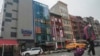 ARCHIVO – Se cree que un edificio de seis pisos con fachada de vidrio, en la foto, segundo desde la izquierda, en el barrio chino de Nueva York, opera un puesto de avanzada de la policía extranjera para China.
