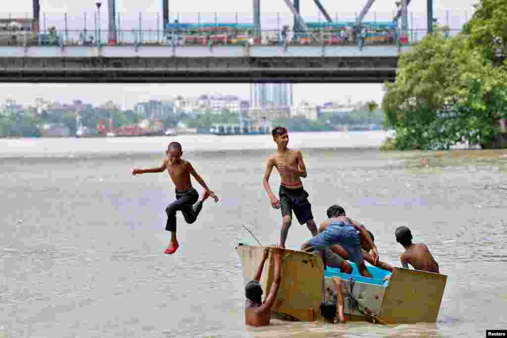 A boy jumps off a boat into the Ganges river to cool off on a hot summer day in Kolkata, India.