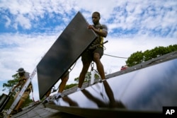 ARHIVA - Zaposleni u NY Stejt Solaru, kompaniji za stambene i poslovne fotonaponske sisteme, postavlja solarne panele na krov, u Masapeku, Njujork, 11. avgusta 2022.