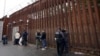 FILE - Federal officers remove handcuffs from men before releasing them through a gate in a border wall to Tijuana, Mexico, March 15, 2023, in San Diego. 