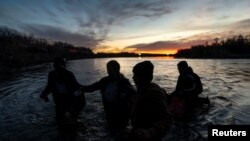 Diely Hernández, de 39 años, quien sufrió una lesión en el pie durante el viaje de tres meses de su familia desde Venezuela, es ayudada a atravesar la corriente del Río Grande por un contrabandista, también conocido como coyote, y su hija Paola Hernández, de 14 años.