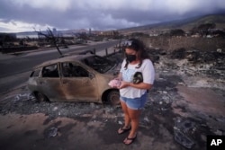 Summer Gerling recoge su alcancía, que encontró entre los escombros de su casa después del incendio forestal del 10 de agosto de 2023 en Lahaina, Hawái.